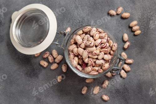 Preview: Glass jar full of dried pinto beans on gray top view, copy space. Traditional Latin American legumes
