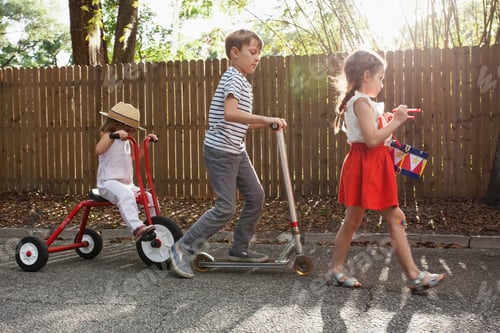 Preview: Three children in mini parade, banging drum, riding tricycle and using scooter