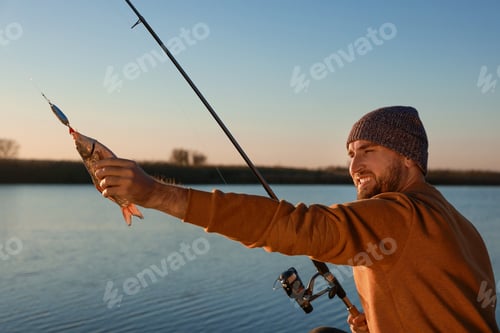 Preview: Fisherman with rod and caught fish at riverside