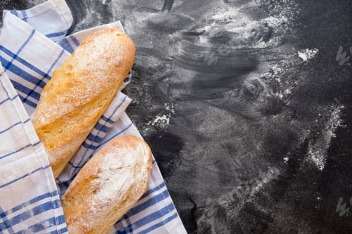 Preview: Sliced bread over dark stone table. View from above with copy space. fresh baked French baguette