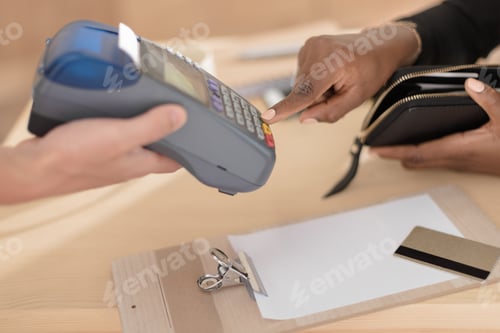 Preview: cropped view of african american woman paying with credit card through terminal in cafe