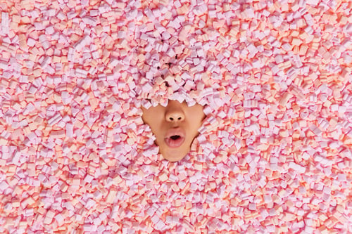 Preview: Hidden surprised unrecognizable human covered with fluffy pink marshmallow only nose and mouth visib