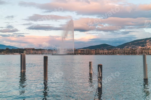 Preview: Scenic view of Jet d'Eau fountain with cityscape and mountains in Geneva during sunset
