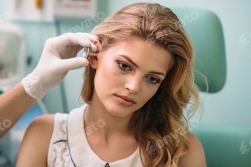 Preview: Young woman receiving an ear examination in a medical clinic during daylight hours