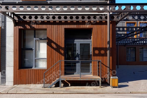 Aperçu: Modern wooden facade with metal accents at urban location during bright daylight