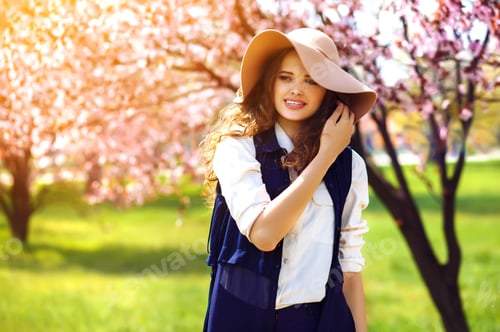 Preview: Outdoor portrait of young beautiful fashionable lady posing near flowering tree.