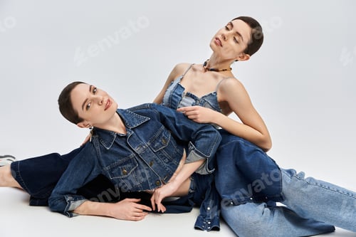 Preview: Twins in fashionable denim showcase elegance and style in playful pose