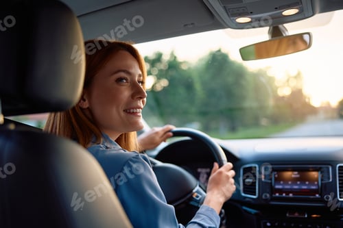 Preview: Happy female driver parking in reverse at sunset.