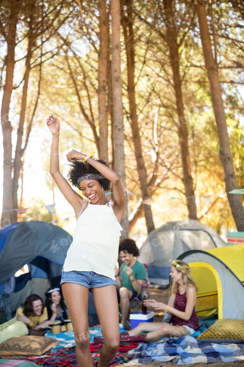 Preview: Cheerful woman standing arms raised while friends sitting in background