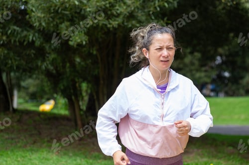 Preview: Woman jogging in park listening to music outdoors