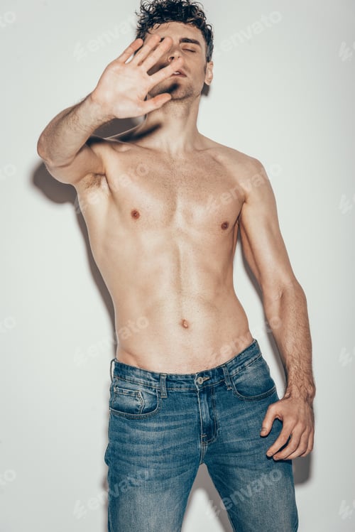 Preview: sexy shirtless man in jeans gesturing and posing on grey