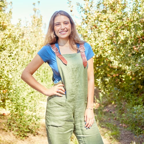 Preview: Portrait of a female farm worker standing on a fruit farm during harvest season. Young smiling farm