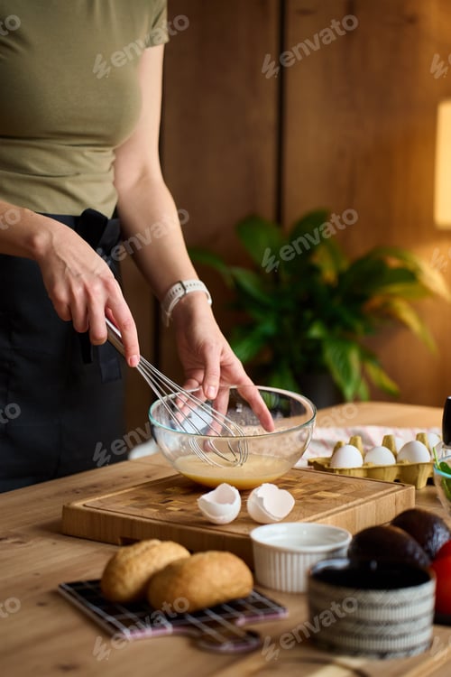 Preview: Person whisking eggs in glass bowl on kitchen counter