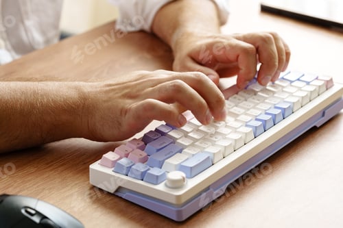 Preview: Person typing on a colorful mechanical keyboard at a wooden desk during daylight hours