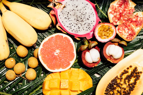 Preview: Fresh exotic fruits on green tropical palm leaves background - papaya, mango, pineapple, passion