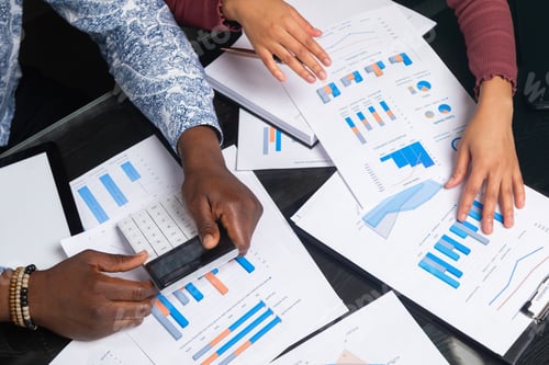 Preview: hands of dark-skinned people hold calculator against background of financial documents in business