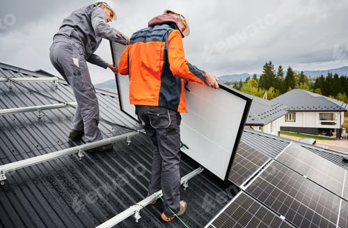 Preview: Technicians carrying photovoltaic solar module while installing solar panel system on roof of house