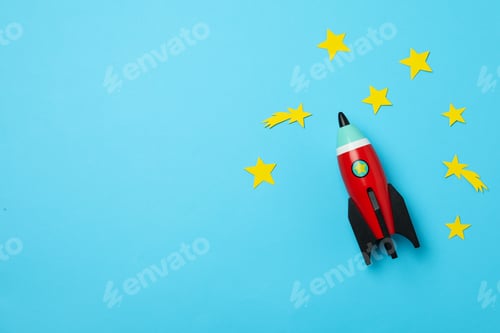 Preview: Bright toy rocket and stars on light blue background, flat lay. Space for text