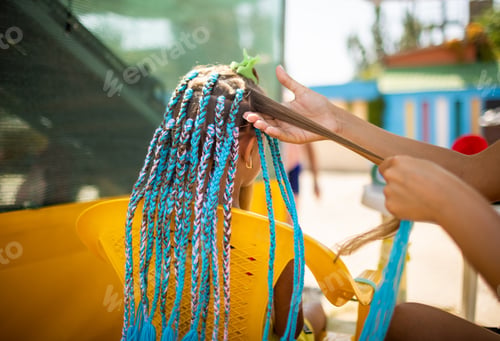 Preview: A girl in a suit weaves African braids in her hair on a sunny day