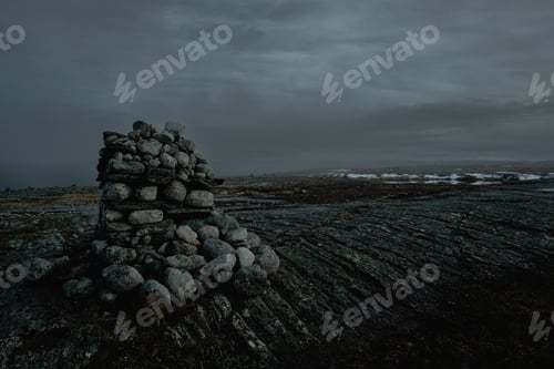 Preview: dark moody landscape cairn stack of stones on top of a mountain at dusk