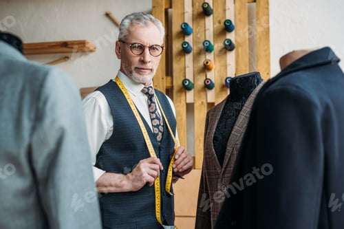 Preview: handsome tailor touching tape measure at sewing workshop