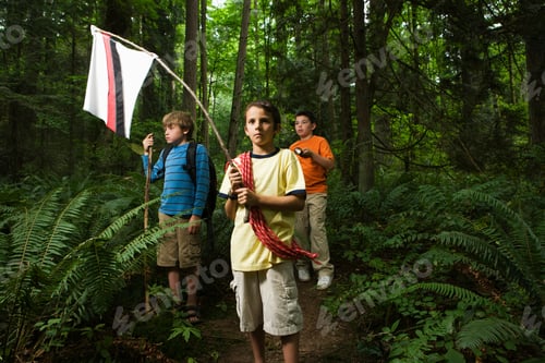 Preview: Young adventurers trek through a lush green forest, flag in hand, on a quest of imagination.