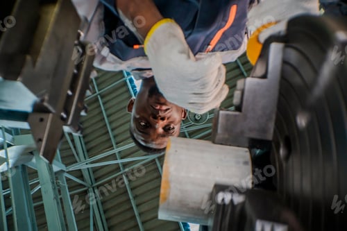 Preview: close up below A factory worker operates heavy machinery