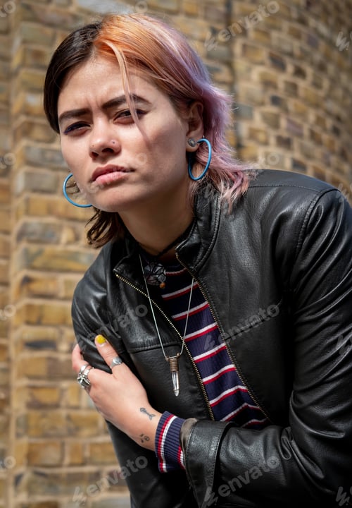 Preview: Mixed race woman looking at camera in front of brick wall.