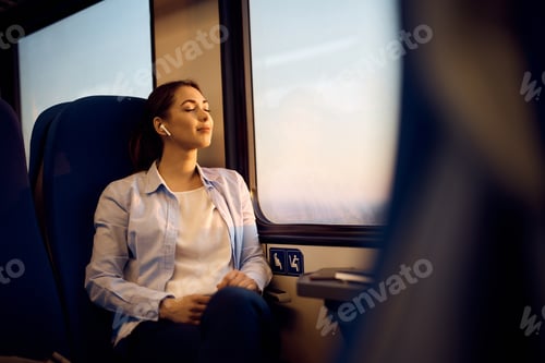 Preview: Woman with eyes closed enjoying by the window in a train during her journey.