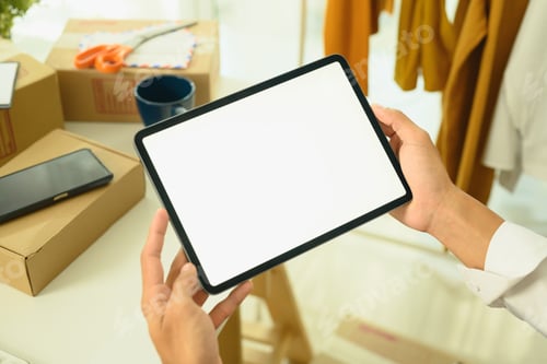 Preview: Young entrepreneur holding digital tablet with blank screen in an e-commerce workspace
