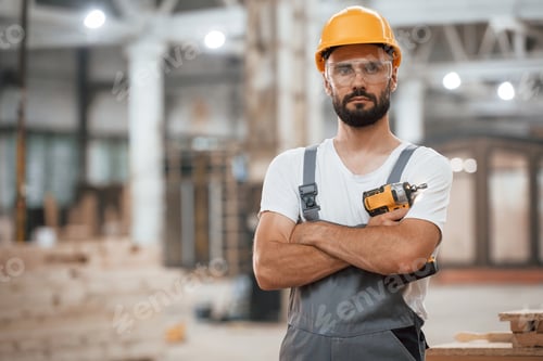 Preview: Standing with arms crossed. Industrial worker in wooden warehouse