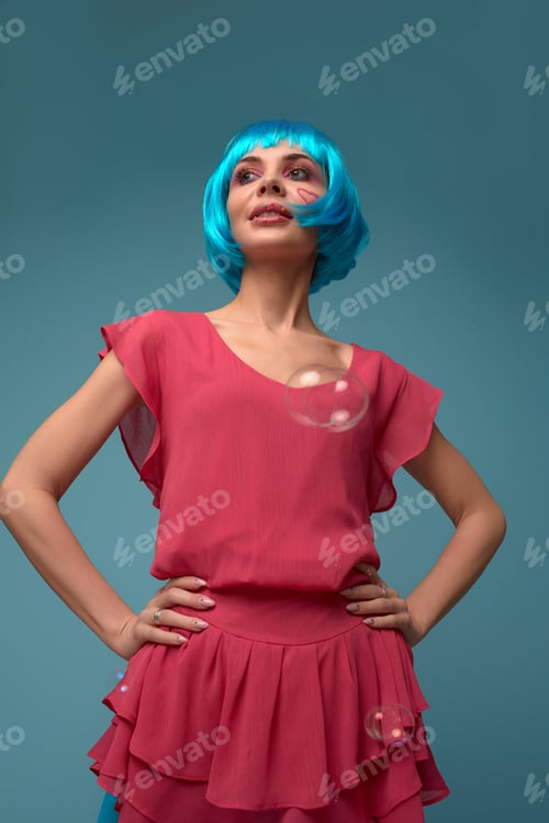 Preview: Beautiful young woman with blue wig and bright make-up in soap bubbles. Fashion model girl with