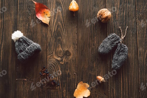Preview: Autumn dried leaves, knitted little hat on wood background. Flat lay