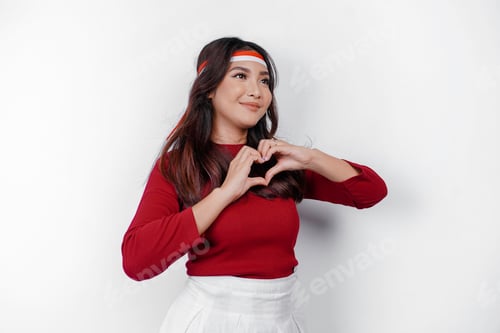 Preview: Young Asian woman feels nationalism, shapes heart gesture. Indonesia's independence day concept.
