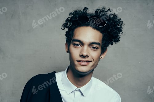 Preview: handsome guy with curly hair in a white shirt and jacket on a gray background photography studio