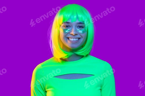 Preview: Young girl wearing neon green top and glitter makeup on cheeks, ready for fancy party
