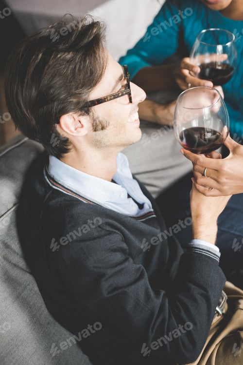 Preview: Young handsome mixed race couple in their house having a glass of red wine