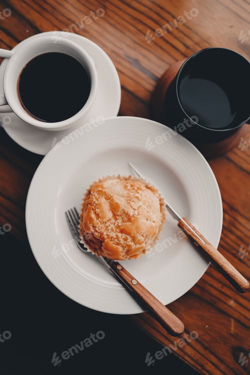 Preview: Vertical shot of a cup of hot coffee and a sweet cookie on the wooden surface