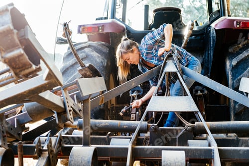 Preview: Young female mechanic repairing tractor at field