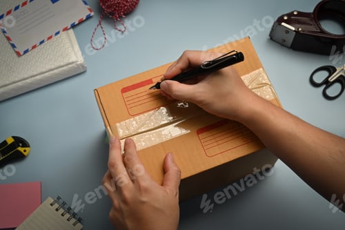 Preview: Cropped image of man writing address on carton box.