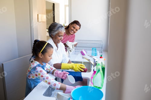 Preview: Grandmother and granddaughter washing utensil in kitchen sink