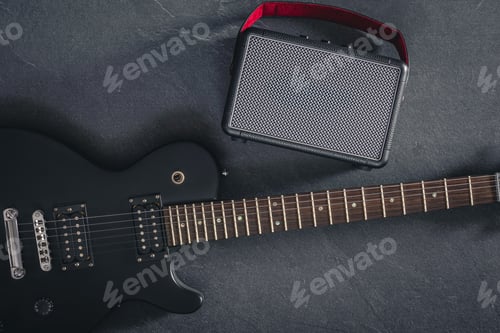 Preview: Electric guitar and speaker on a textured black background, top view.