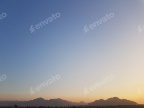 Preview: Expansive blue sky providing a backdrop to a mountain range on the horizon