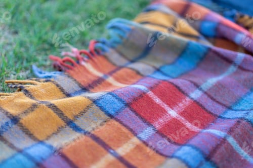 Preview: Picnic blanket lies on the grass on a sunny day. Wool checkered picnic blanket