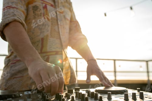 Preview: Hand of young man mixing sounds by soundboard outdoors