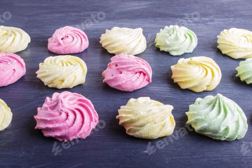 Preview: set of colored meringues on black wooden background. geometric pattern.