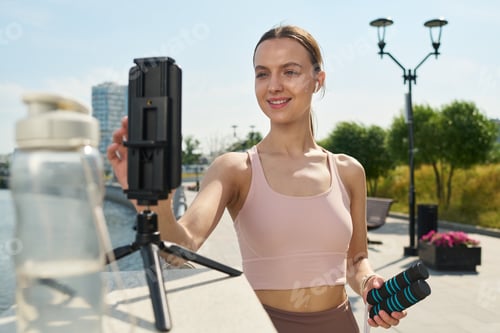 Preview: Young Woman Recording Fitness Video Outdoors Using Smartphone Tripod