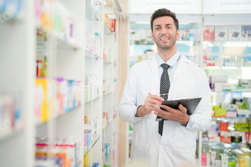 Preview: pharmacist wearing lab coat carefully selects medication in a pharmacy.