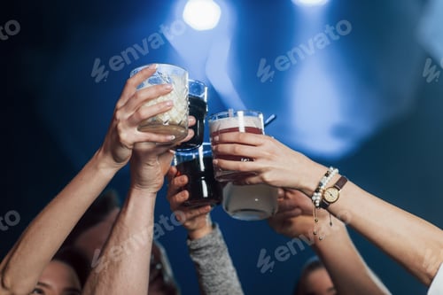 Preview: Variety of drinks. Group of young friends smiling and making a toast in the nightclub