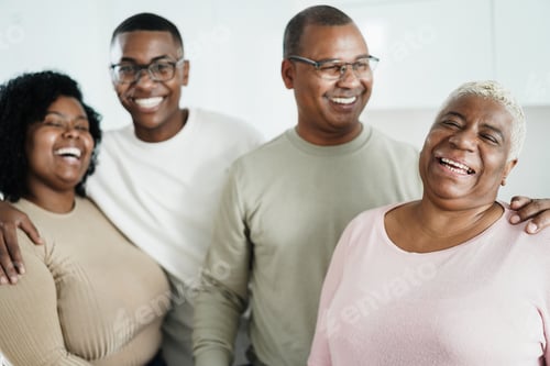 Preview: Happy african family smiling in front of camera at home - Focus on mother face